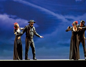 Das Szenenfoto zeigt zwei gleich gekleidete Paare auf einer Bühne