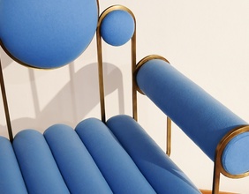 Ein designer Sessel in blauem Stoff und Messing Rahmen.