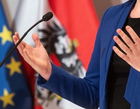 Diskutierende Hände, Mikrofon und Fahnen im Hintergrund