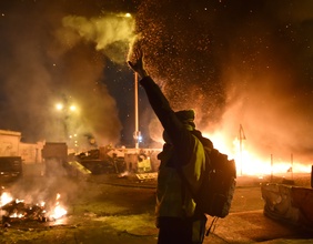 "gilets jaunes"-Demonstrant, dahinter brennende Flächen