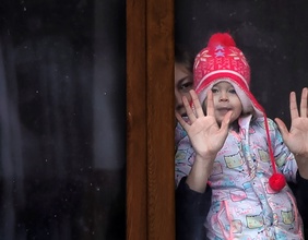 Frau mit Kind hinter einer Fensterscheibe