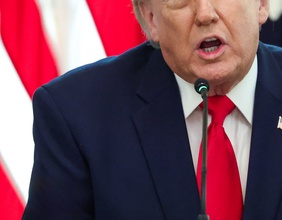Donald Trumps Oberkörper und Mundpartie, dahinter US-Flagge