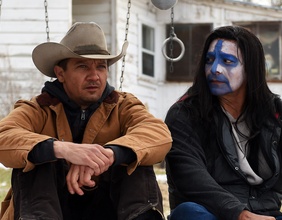  Jeremy Renner mit Cowboyhut und Indianer mit Gesichtsbemalung