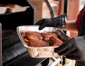 Eine Aluschale mit Grillgut wird bei einem BBQ-Bewerb gehalten