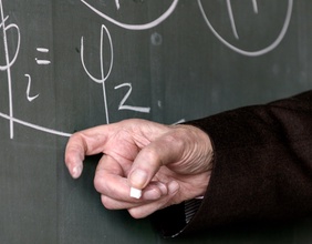 Gleichung auf einer Tafel und Hand mit Kreide