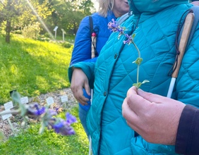 Mann hält Blume, dahinter Frau mit Blindenstock im botanischen Garten