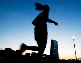 Bild einer Läuferin die bei Tagesanbruch durch die Stadt läuft.