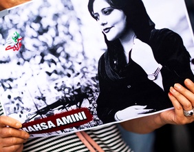 Ein Frau hält ein Bild von Mahsa Amini