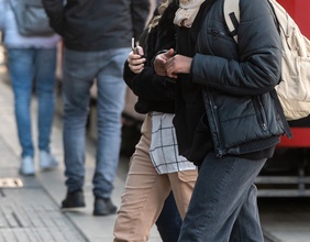 Junge Leute auf der Straße neben einer Straßenbahn - Passantinnen