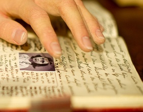 Eine Wachsfigur von  Anne Frank, die in ihrem Tagebuch schreibt