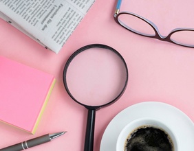 Post-it, Lupe, Zeitung und eine Tasse Caffe