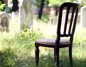 Ein Stuhl steht auf einem Friedhof zwischen Grabsteinen