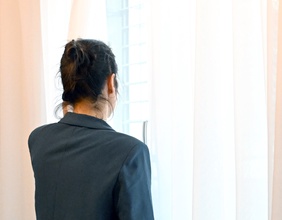 Frau schaut aus dem Fenster, Vorhang