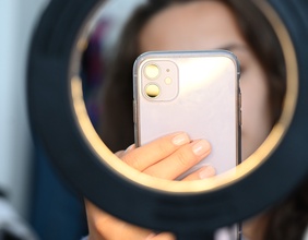 Junge Frau mit Smartphone und Ringlicht