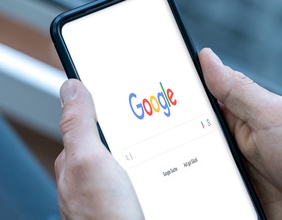 Mann hält Smartphone in Händen - Google Searchbar