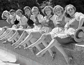 Frauen sitzen aufgereiht auf einer Steinmauer und posieren bei den Salzburger Festspielen 1946