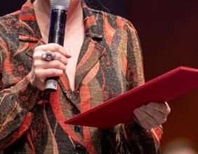 Frau hält Mappe und Mikrofon in Händen