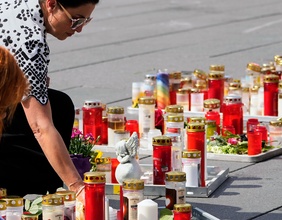 Menschen stellen Kerzen in Gedenken auf