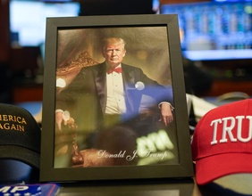 Foto von Donald Trump in einem Bilderrahmen neben MAGA-Kappen