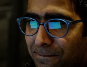 Ein Bildschirm spiegelt sich in den Brillen eines Mannes.