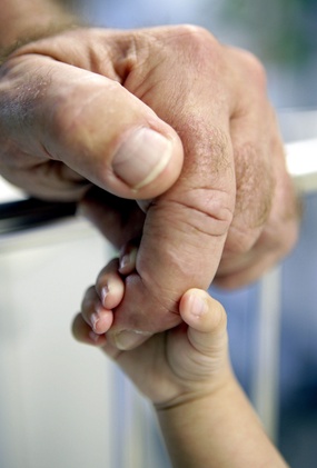 Babyhand hält den Finger eines Mannes fest