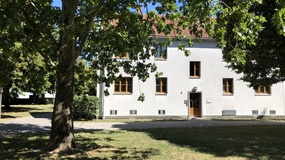 Haus mit heller Fassade in einem begrünten Hof