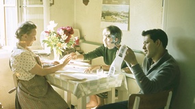 Frau mit zwei Jugendlichen am  Küchentisch