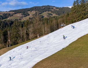 Skipiste mit Kunstschnee, links und rechts Wiese