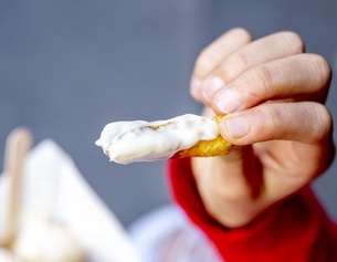 Hand hält Pommes Frites mit Mayonnaise