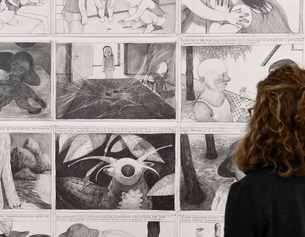 Eine Frau betrachtet Zeichnungen von Anke Feuchtenberger