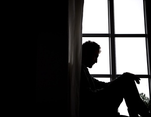 Ein Mann sitzt an einem Fenster.