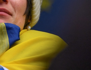 Weinende Frau in eine ukrainische Flagge gehüllt