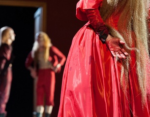 REINHARD WERNER/BURGTHEATER Person im roten Kleid miz blutigen Händen, im hintergrund zwei Figuren