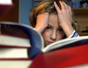 APA/ROBERT JAEGER Ein Kind sitzt verzweifelt vor Schulbüchern.