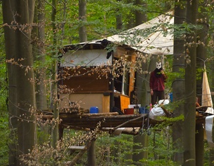 APA/AFP/PATRIK STOLLARZ Mann mit Maske in einem Baumhaus