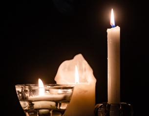 Drei Kerzen brennen im Dunkeln.