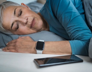 Schlafende Frau mit Smart Watch und Handy
