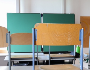 Klassenzimmer: Hochgestellte Stühle und Tafel