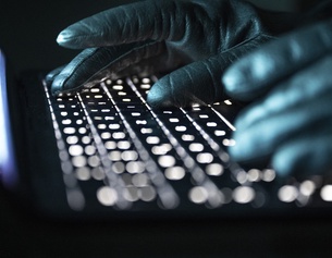 Hände in Handschuhen auf der Tastatur 