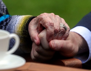 Ein Mann hält die Hand einer älteren Frau.