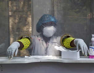 AP/MAHESH KUMAR A Frau im Gesundheitsdienst in Indien hinter Plexiglas