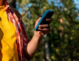 Mann mit Smartphone beim Wandern