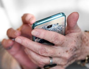 Die Hände einer älteren Dame mit einem Smartphone