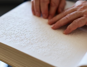 Eine Frau liest ein Buch für Blinde