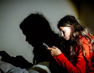 Mädchen sitzt und schaut auf ihr Handy