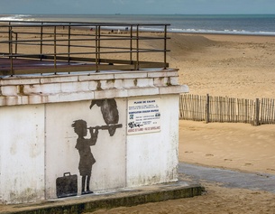 AFP/PHILIPPE HUGUEN Strand von Calais 2015: Kind mit Koffer blickt durch ein Fernrohr, darauf sitzt ein Geier