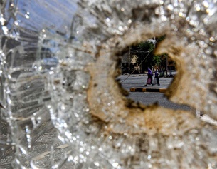 Zerstörtes Glas, dahinter Blick auf zwei Frauen im Sudan