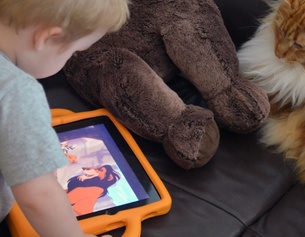 Kind mit iPad, Teddybär und Katze