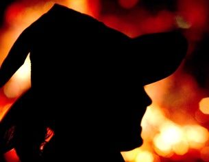 Eine Frau mit Hexenhut vor einem Feuer