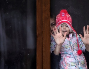 Frau mit Kind hinter einer Fensterscheibe